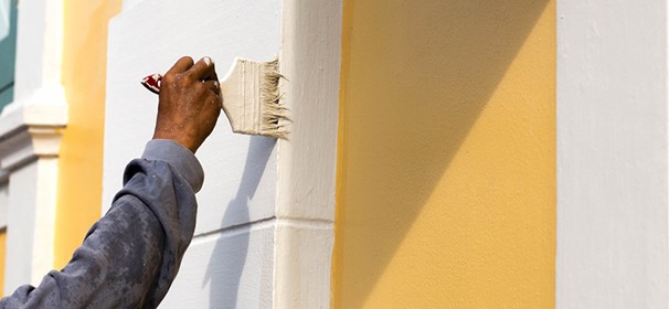This is an image of a person painting a wall to improve the curb appeal of their home