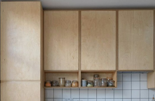 plywood kitchen cabinets with a shelf full of spice jars
