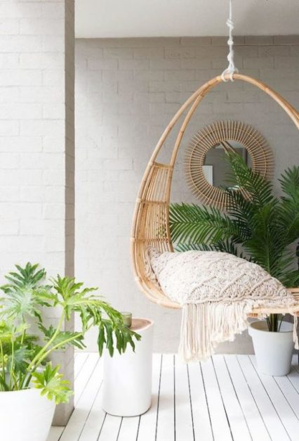 cane swing set up with cushion and plants outdoors