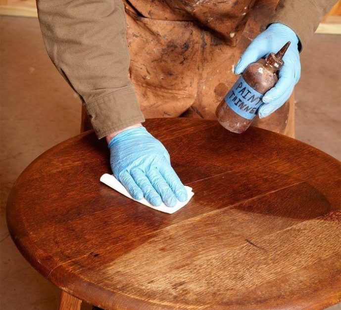 a person polishing the surface of a wooden stool