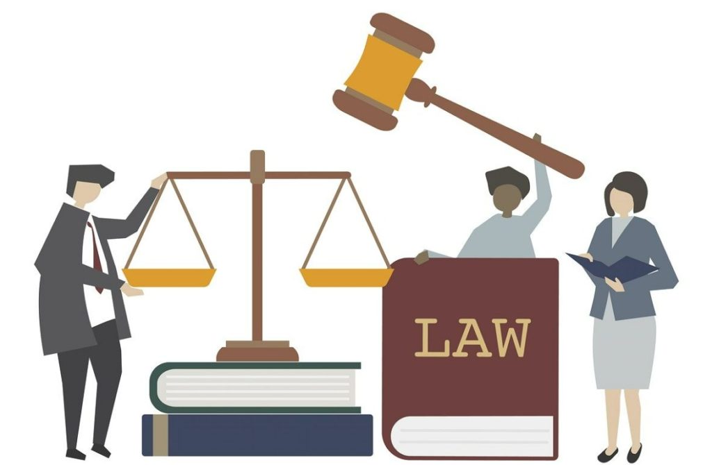 Three people stand beside a balance and books to illustrate law
