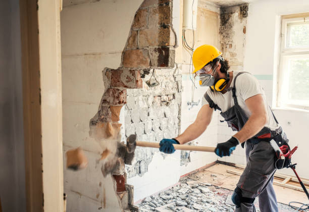 گھر کی مرمت کے دوران معمار ہتھوڑے سے دیوار توڑتے ہوئے