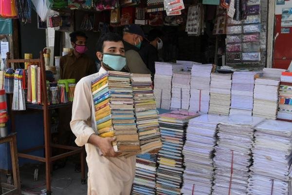 boy holding bunch of books at Paper market