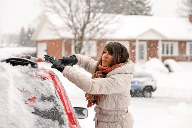 ایک خاتون اسکریپر کے ذریعے گاڑی سے برف ہٹاتے ہوئے