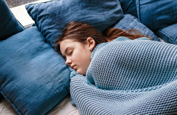 سردی میں نرم بستر، کمبل اور تکیوں کے ساتھ گہری نیند سوتی ایک لڑکی